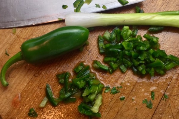 cut up green onion on a brown cutting board