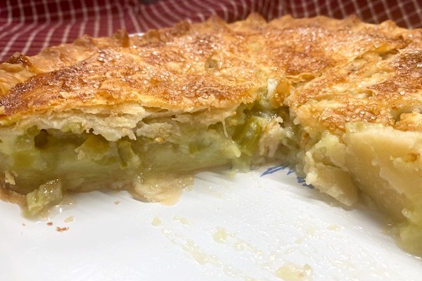 double crust rhubarb custard pie with a slice taken out on a white plate.