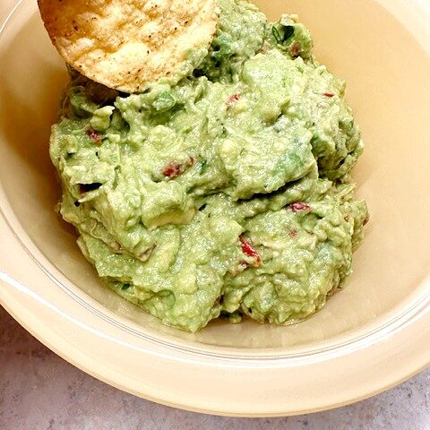 holy guacamole in yellow bowl with a chip