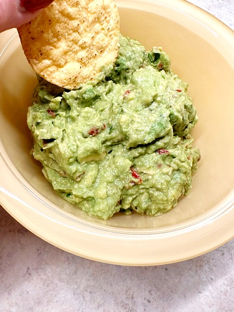holy guacamole in yellow bowl with a chip