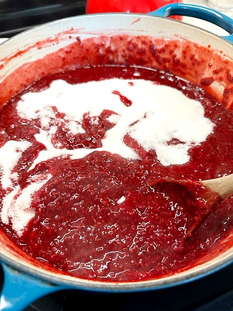 adding sugar to the jam